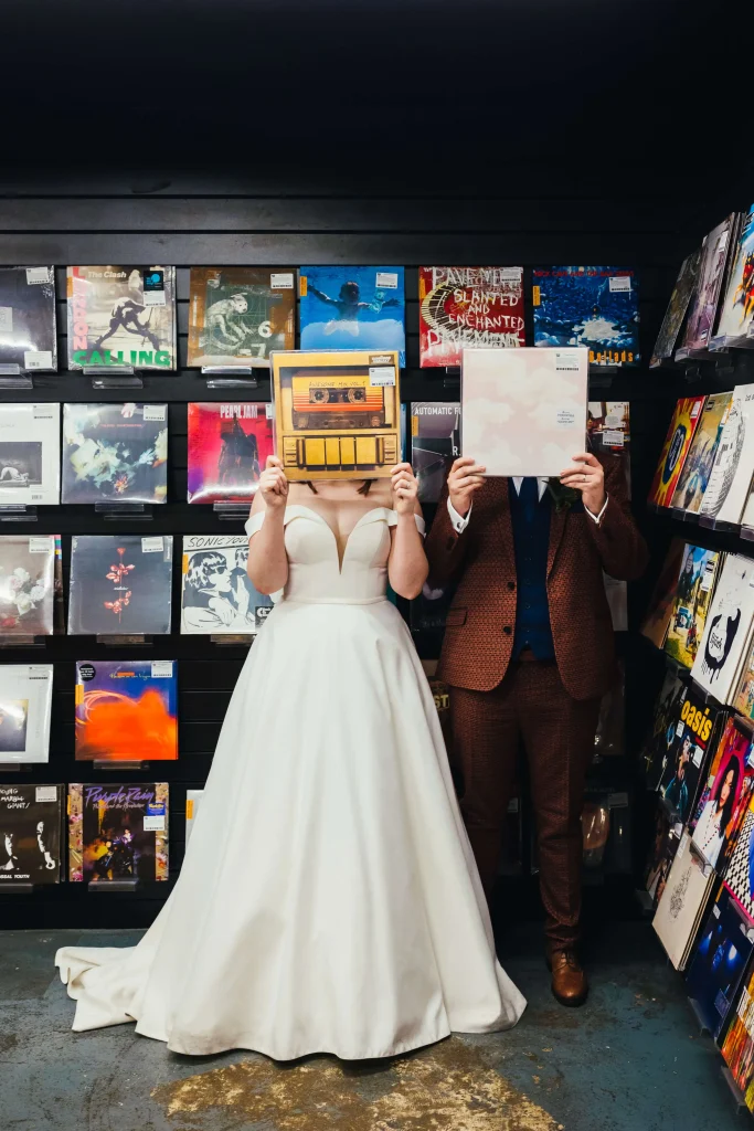 Couple in Rough Trade in Nottingham during their couples portraits. They are both holding their favourite albums in front of their faces