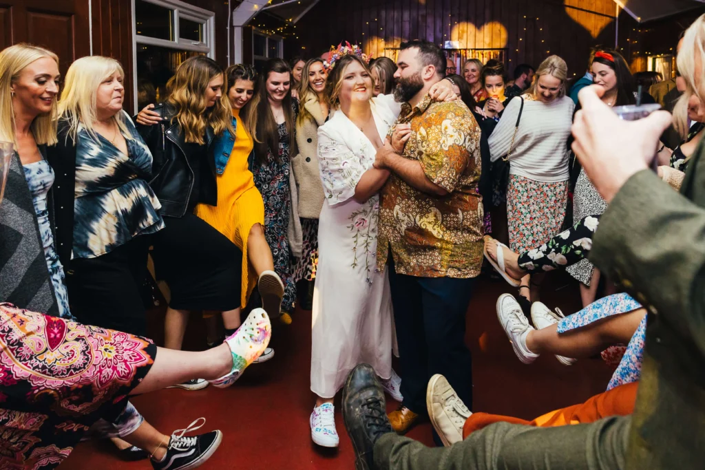 Couple embracing on the dancefloor whilst guest kick their legs towards them can can style.