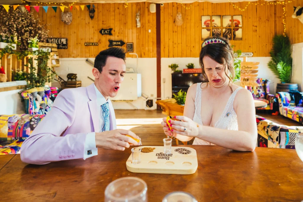 Couple taking a moment away from their guests to do shots together. Both are pulling funny faces as the taste hits them.