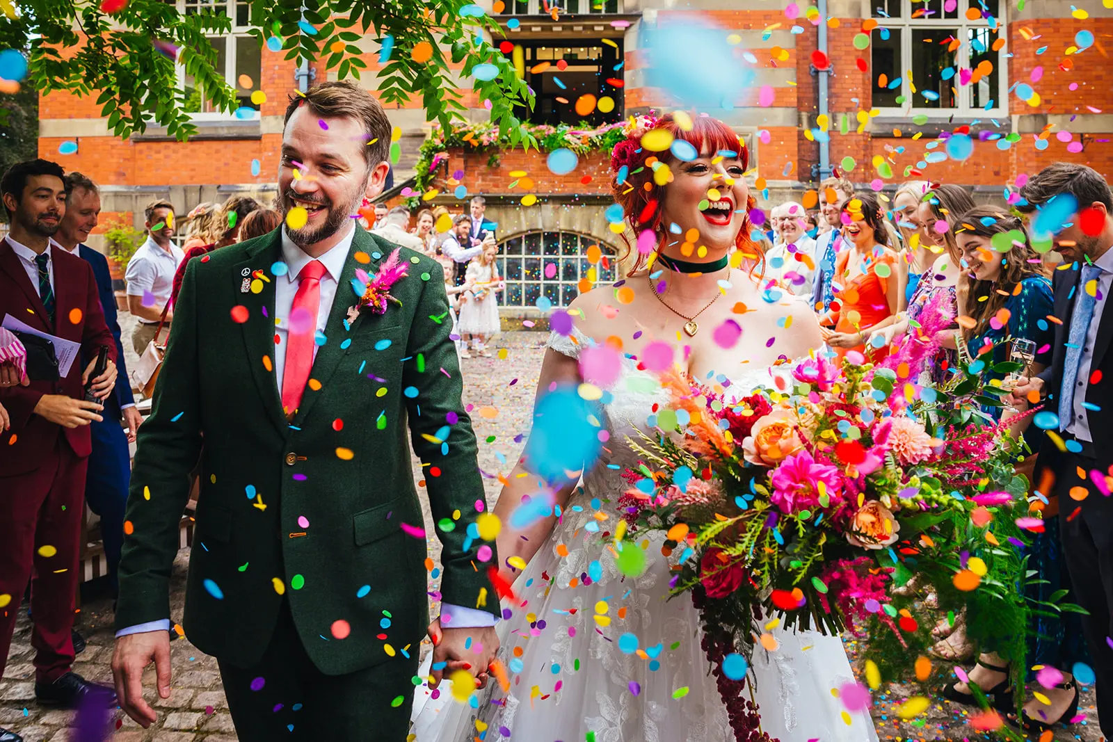 Couple walking through bright rainbow confetti at their wedding