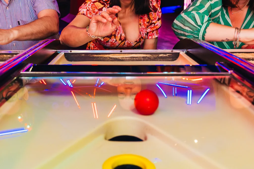 Wedding guest playing arcade game you ca see her excited expression in the reflection of the glass of the game.