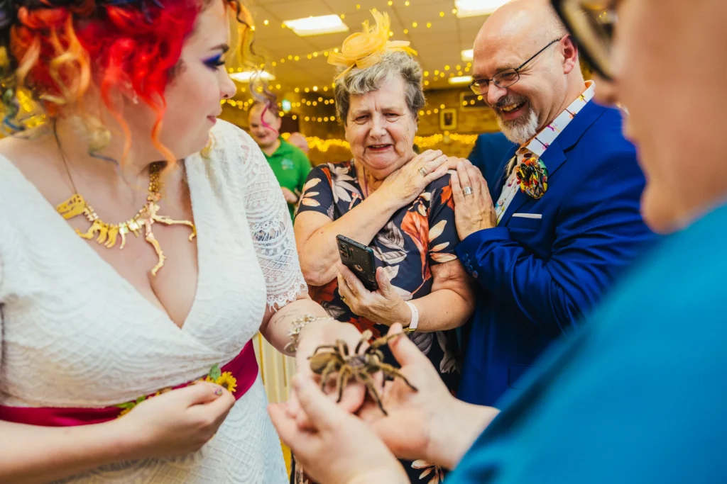 Bride and guest holding Tallula the tarantula whilst the groom comforts a guest who's a bit scared in the background.