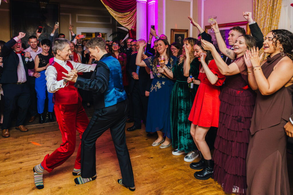 Couples first dance at Langar hall their both wearing socks without shoes and their guests are surrounding them and cheering them on