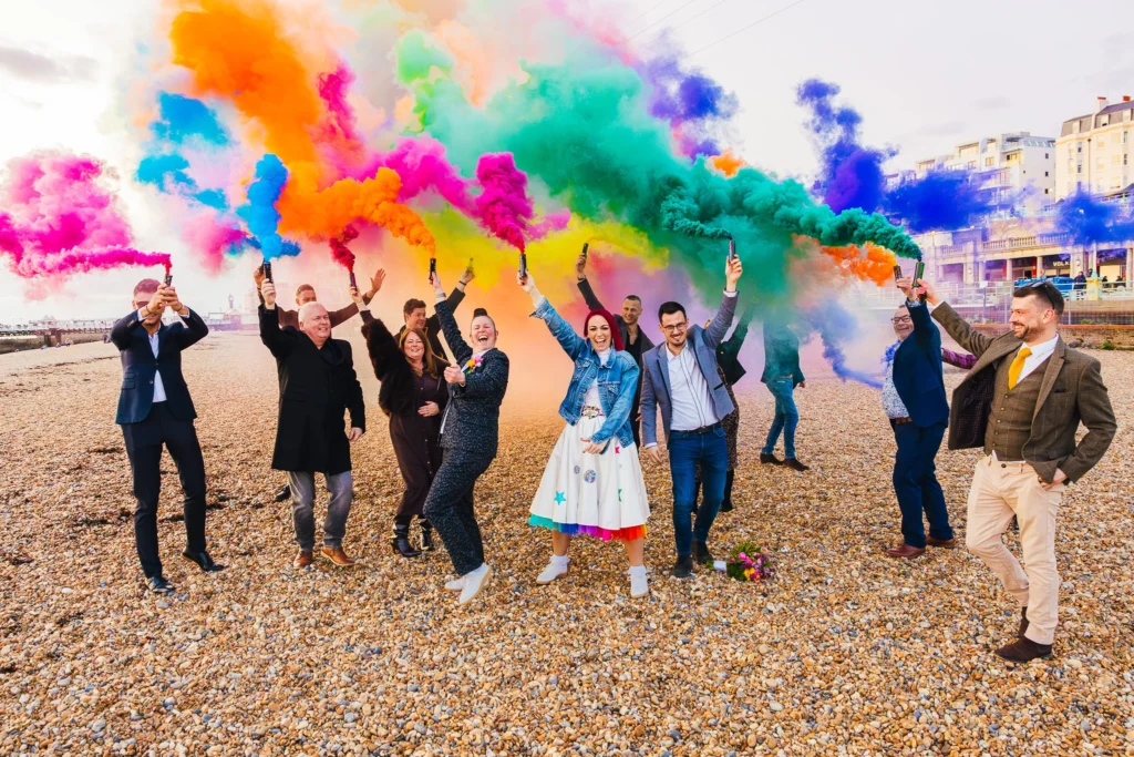 Couple on Brighton beach with thier guests they have rainbow smoke and they're dancing around you can feel the joy
