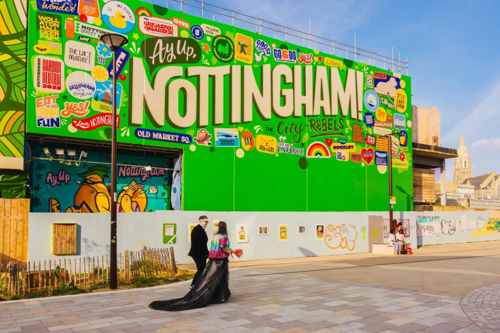 Couple walking by giant green Nottingham sign on their wedding day
