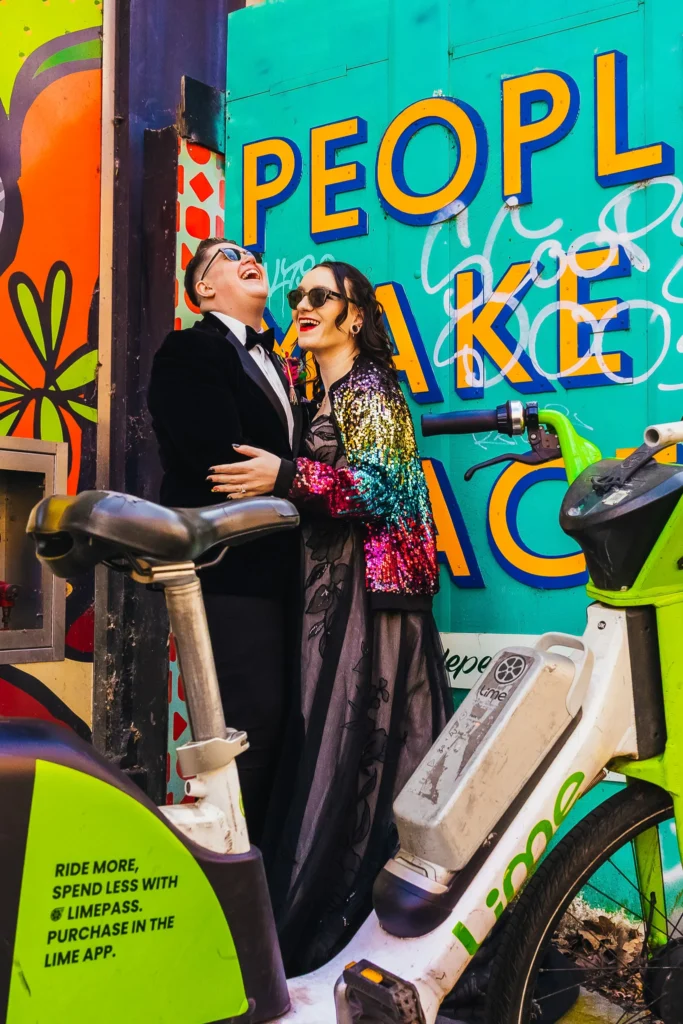 Couple stood in front of green graffiti wall framed by a lime bike