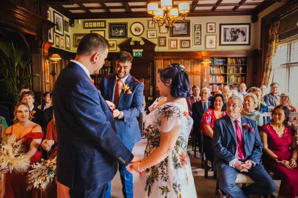 brides brother handing wedding rings to couple during their ceremony with all the other guests looking on