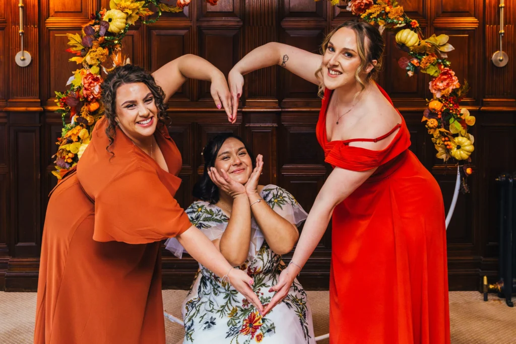 Bridesmaids are using their arms to make a heart around bride whos got her hands framing her face. It's a fun group shot