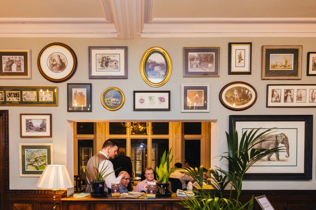 this pictures shows the wedding guests sat talking to each other it's taken through a hatch in the lobby of the hotel it's framed by pictures of all the animals at the zoo