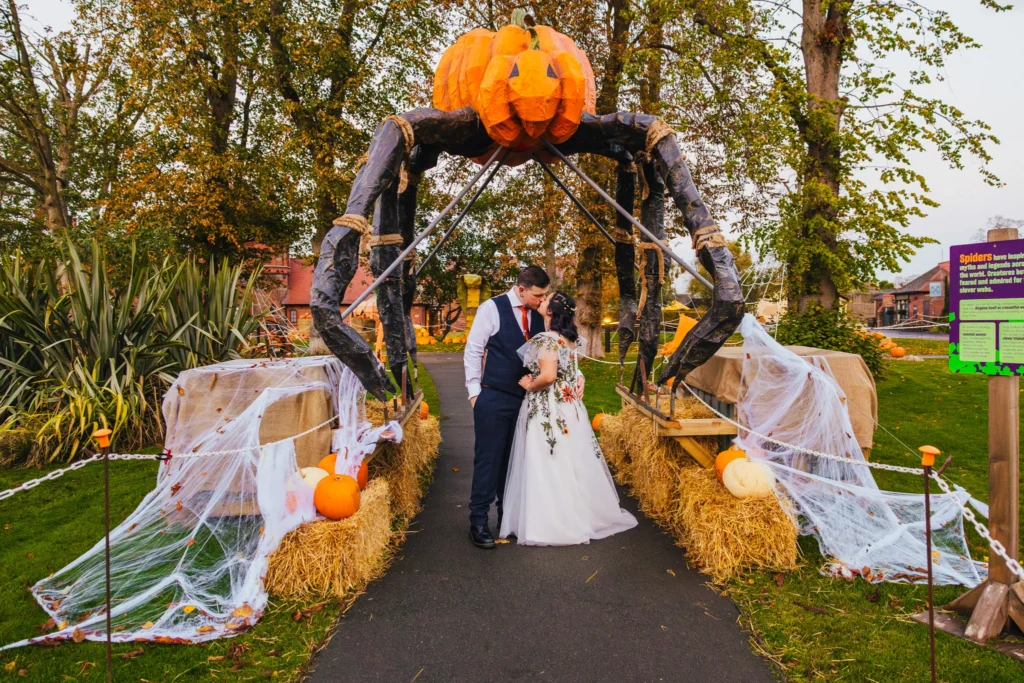 couple are stood under a halloween display at Chester Zoo. They have a giant pumpkin spider above their heads