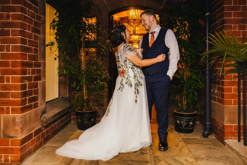 Couple stood together laughing as the evening shenanigans at their wedding are about to begin