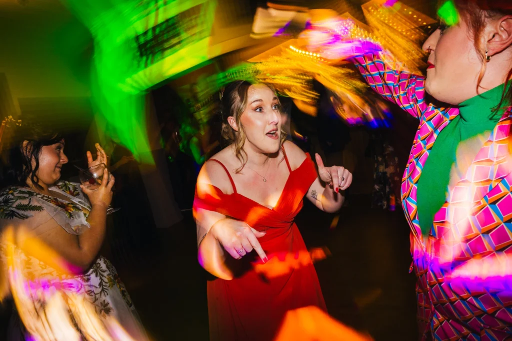 Maid of honour is busting a move on the dance floor she is backed by light trails and has a guest dancing with her
