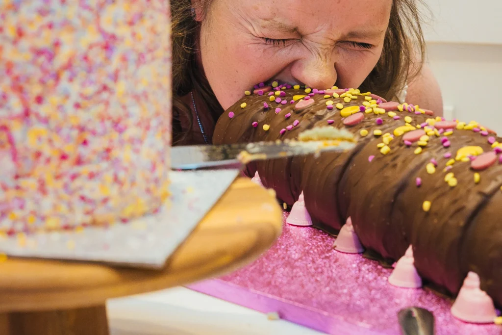 Close up as bride takes bite out of the bum of a Connie the caterpillar cake during cake cut at her wedding.