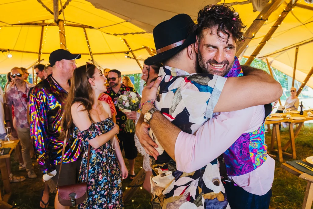 Couple greeting guests after their festival wedding ceremony. Everyone is wearing bright clothes and big smiles
