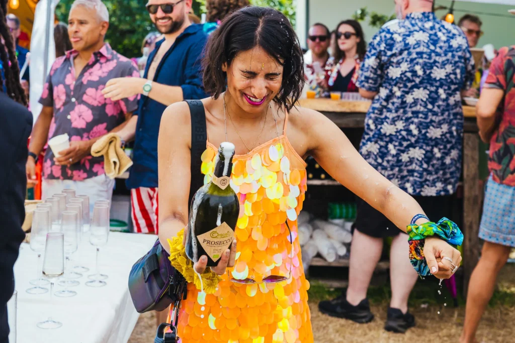 Guest in gorgeous orange dress stands covered in prosecco after it popped a little more than she expected