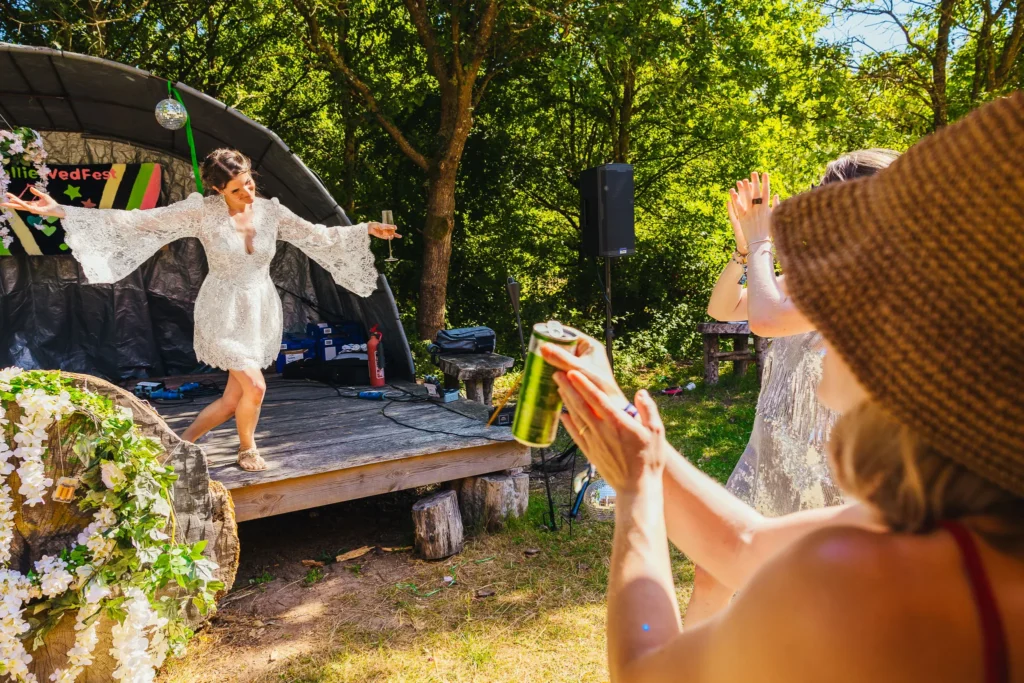 Bride taking a bow after a quick karaoke session on stage at her wedding whilst guests clap