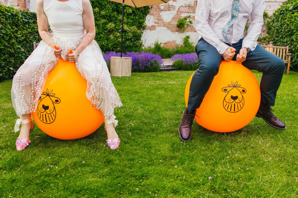 Couple having space hopper race during their wedding reception you can't see their faces but you can see the brides amazing flowery shoes