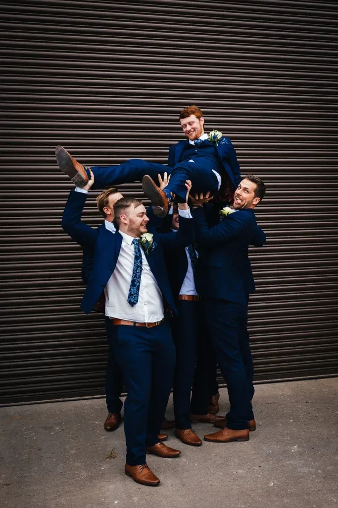 Groom being lifted by his groomsmen