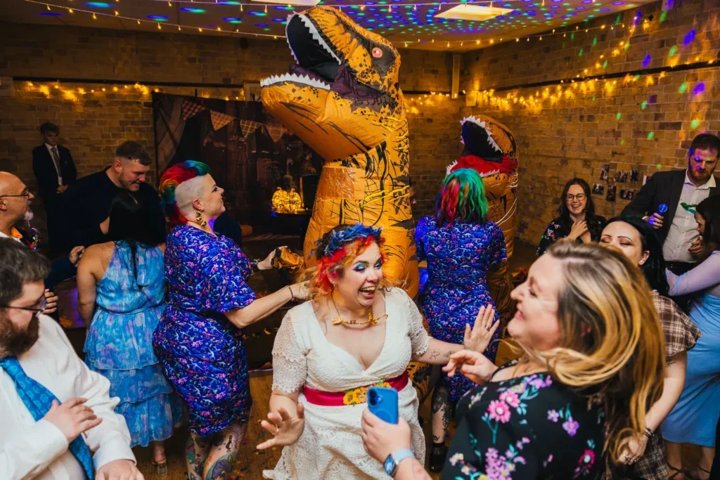 Bride dancing with guests and inflatable dinosaurs