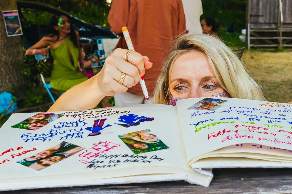 Guest signing a colourful guest book at a festival wedding
