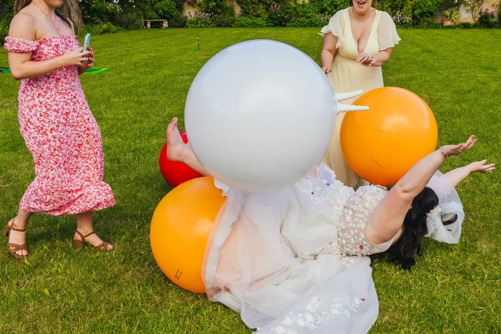 Bride falling over space hoppers in a walled garden