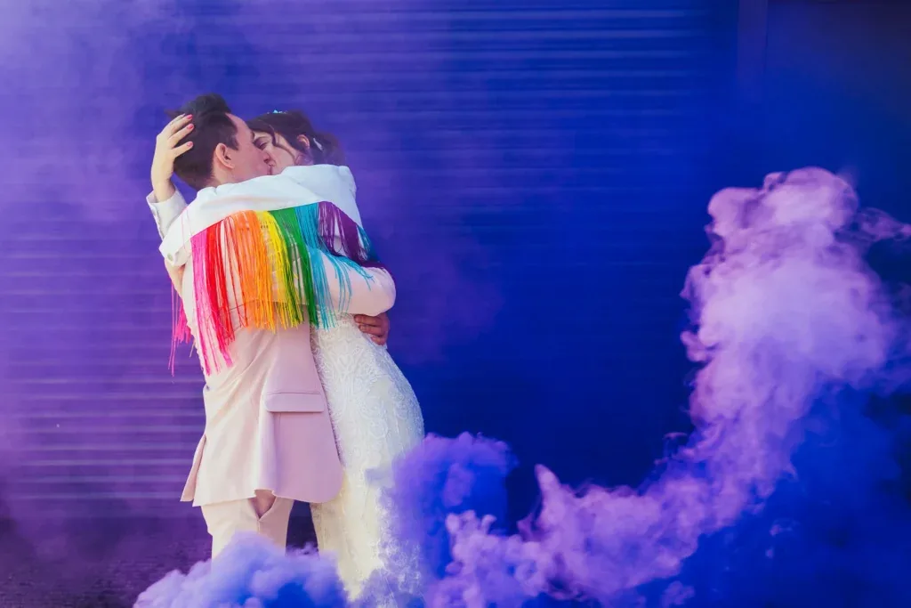 Couple in rainbow fringe and purple smoke at Wellbeing Farm